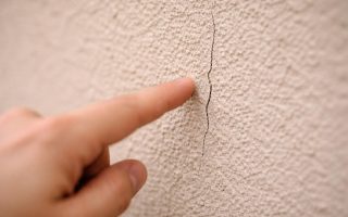 mur-enduit-fissure-main-floue