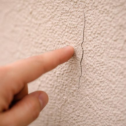 mur-enduit-fissure-main-floue