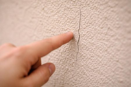 mur-enduit-fissure-main-floue